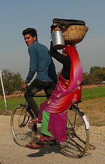 Inderin mit Kopflast auf dem Fahrrad - Streetlife in Indien
